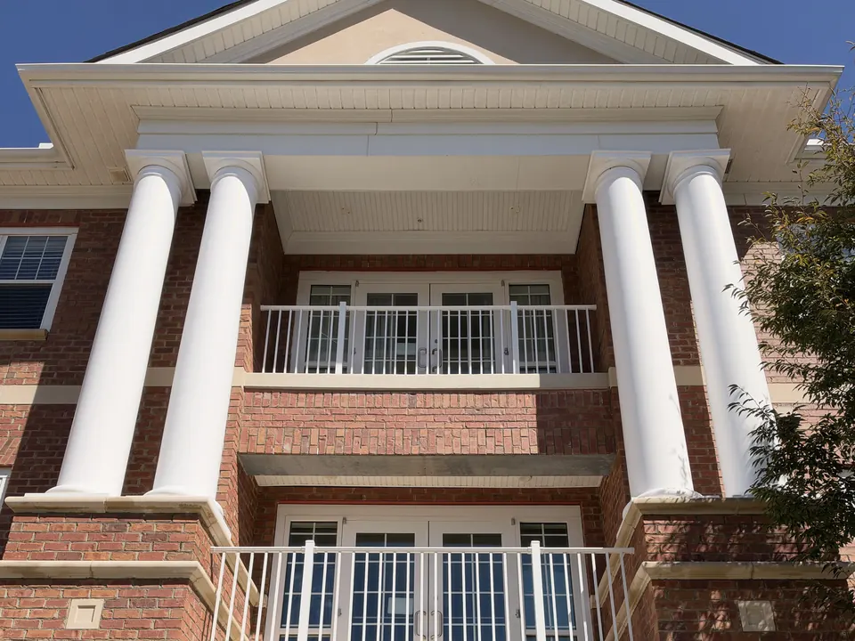 Brick building entrance with tall white columns and balconies