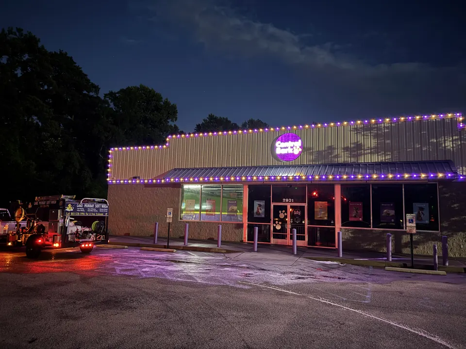Storefront with purple lights and the Lake Murray Soft Wash trailer at night