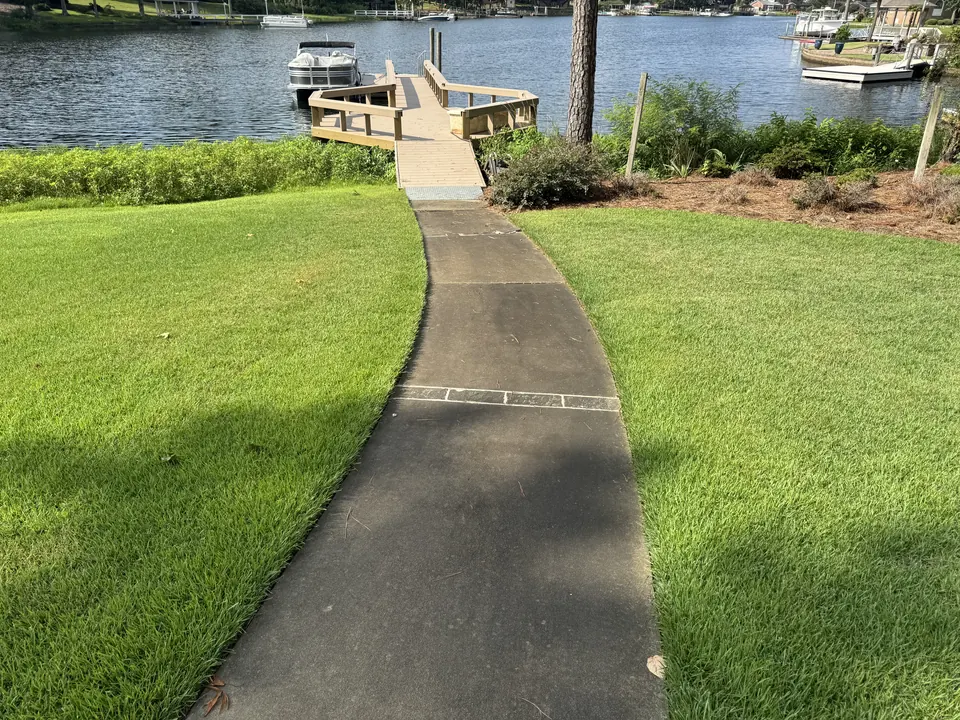 Dark algae-covered concrete walkway to a lake dock before cleaning