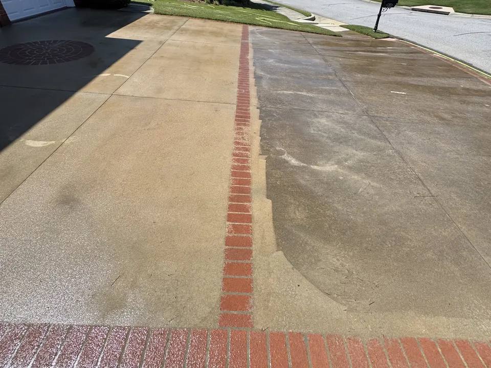 Concrete driveway with a brick border, cleaned on one side and not yet on the other
