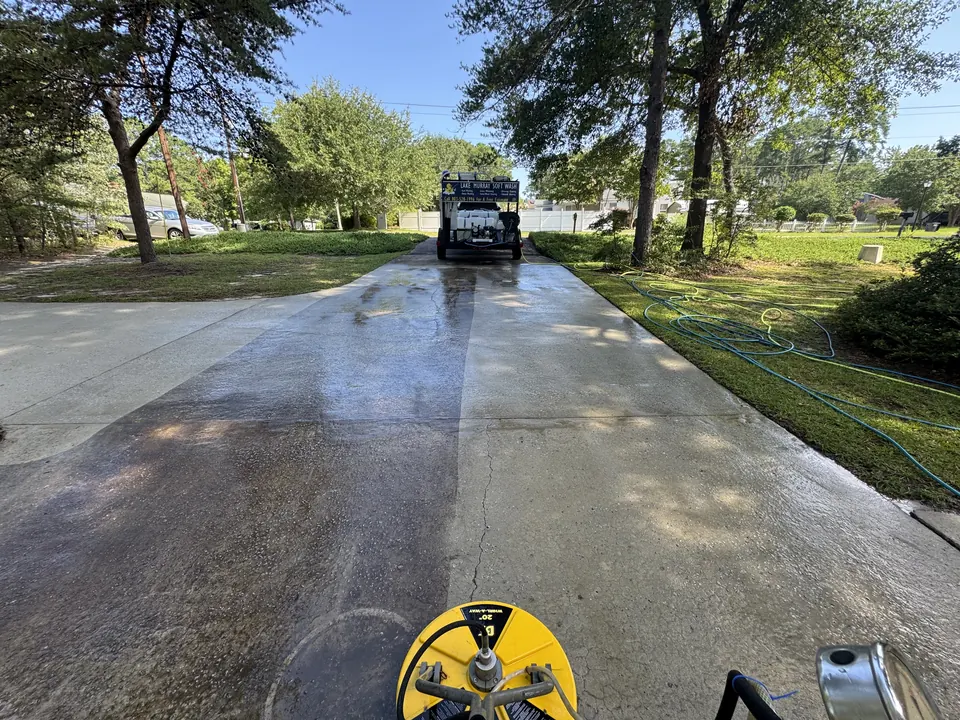Concrete driveway half cleaned, showing a clean stripe next to dirty concrete