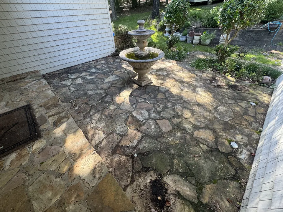 Dark, dirty flagstone patio with a fountain before cleaning