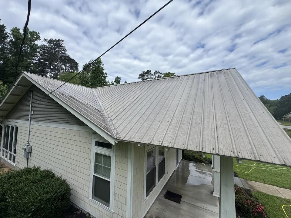 Metal standing-seam roof with dark streaks and dirt before cleaning