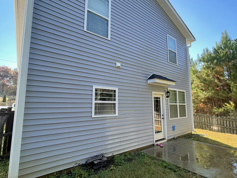 Same gray vinyl siding clean after washing, with a wet patio below