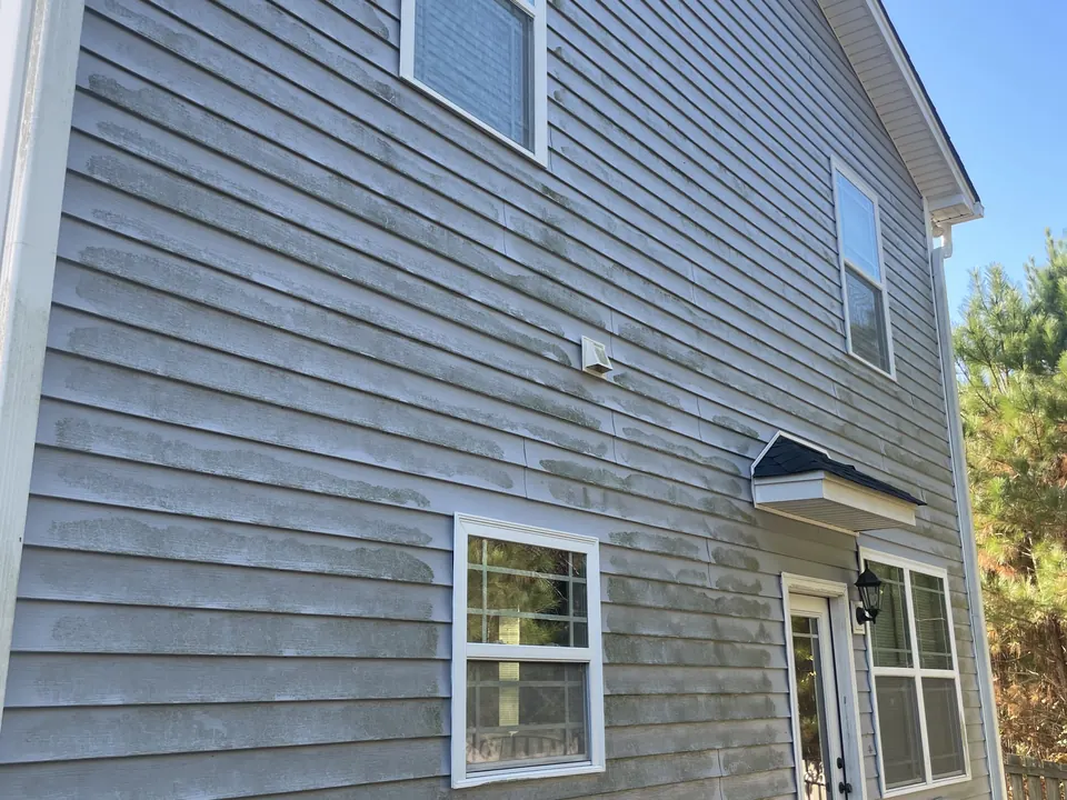 Gray two-story vinyl siding with algae buildup before washing